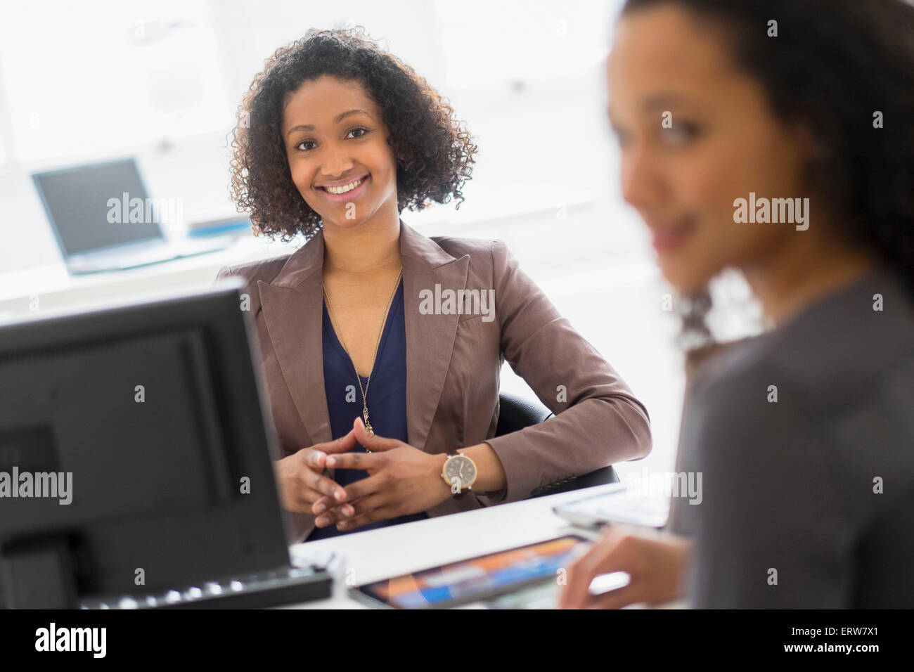 Geschäftsfrauen, die lächelnd im Büro treffen Stockfoto