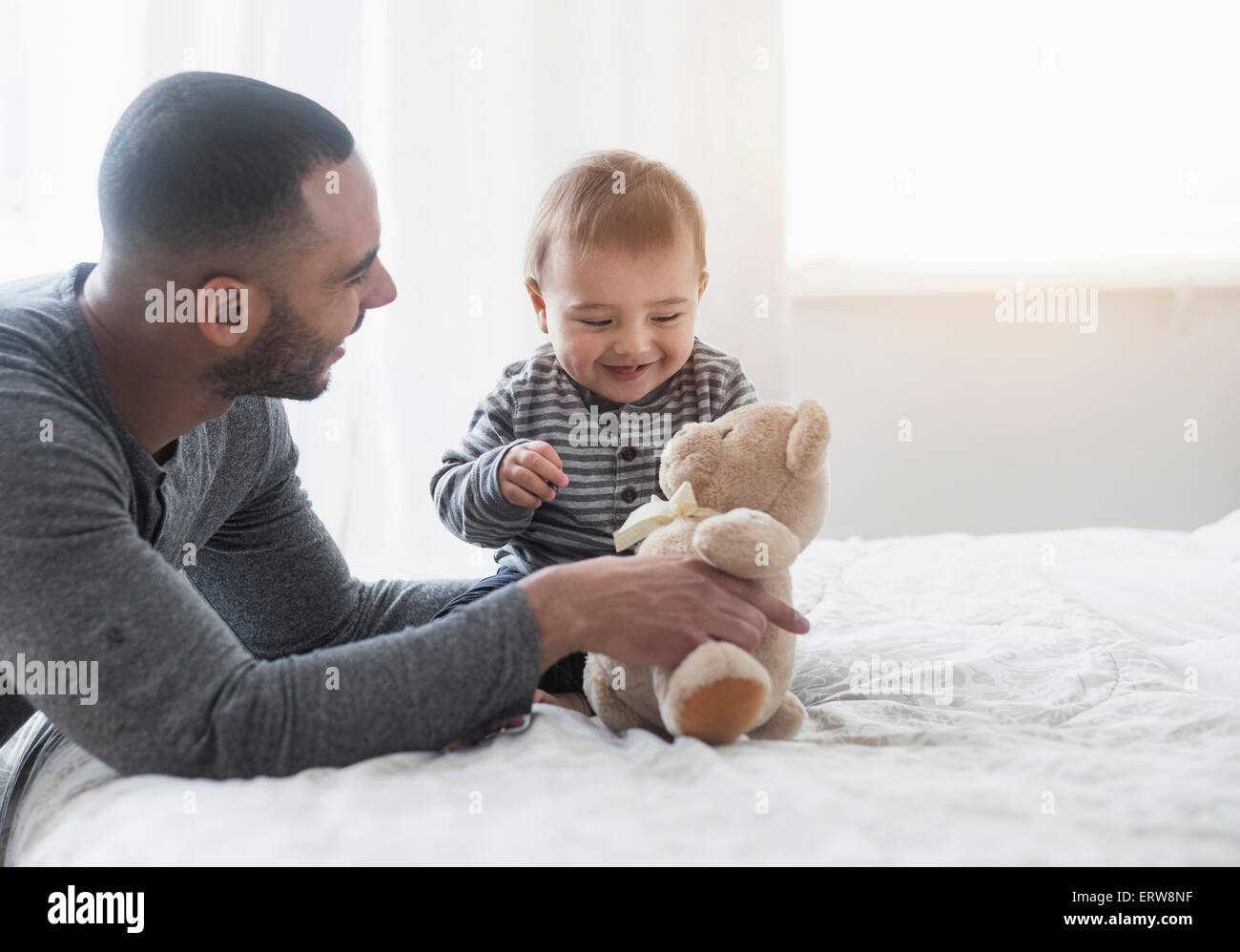 Lächelnden Vater spielen mit Baby Sohn auf Bett Stockfoto