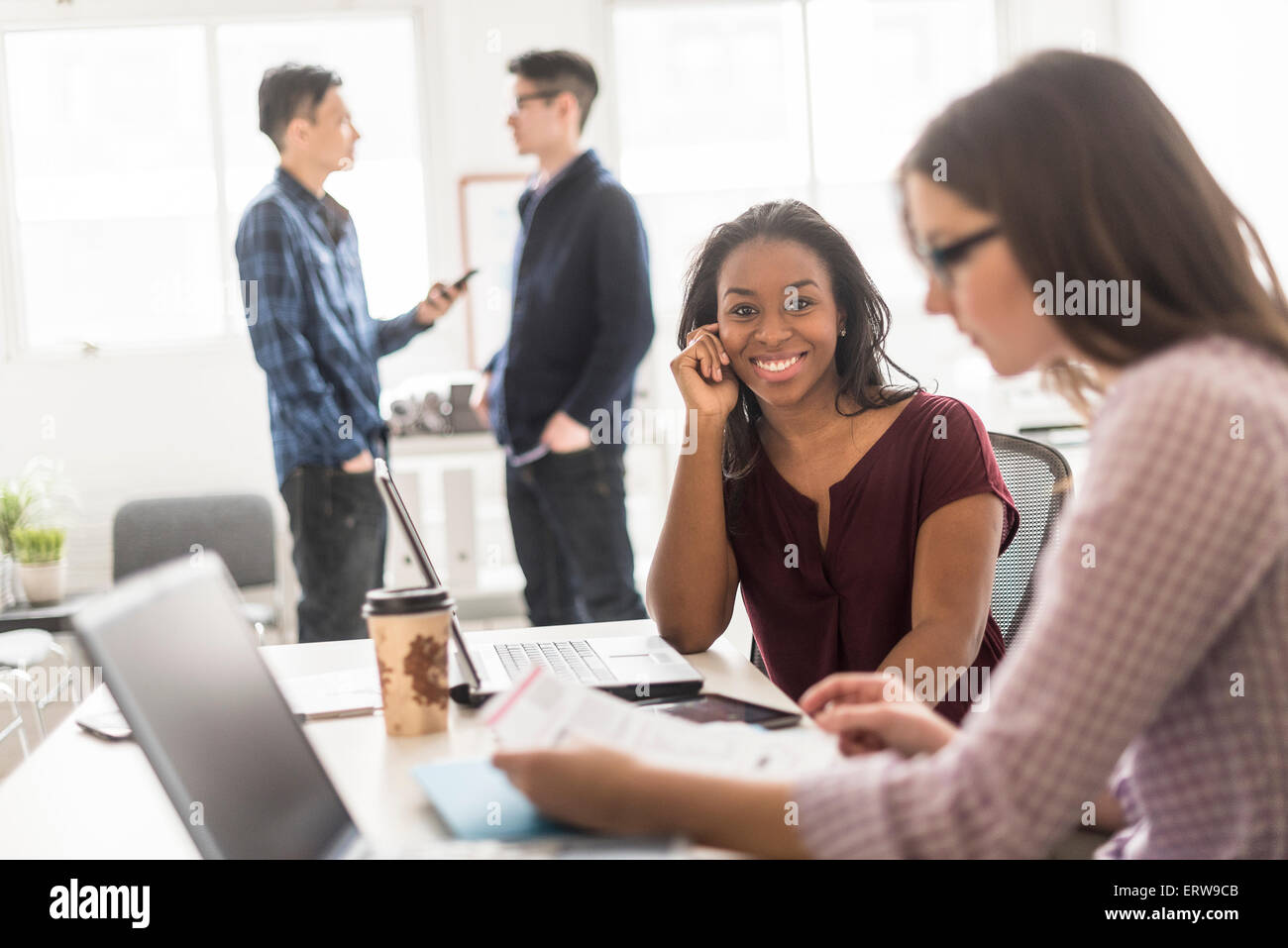 Geschäftsfrau, die lächelnd mit Technik im Büro Stockfoto
