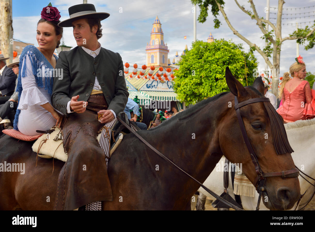 Gut aussehender Mann und schöne Frau auf dem Pferderücken mit 2015 Haupttor des spanischen Sevilla April Fair trinken Stockfoto