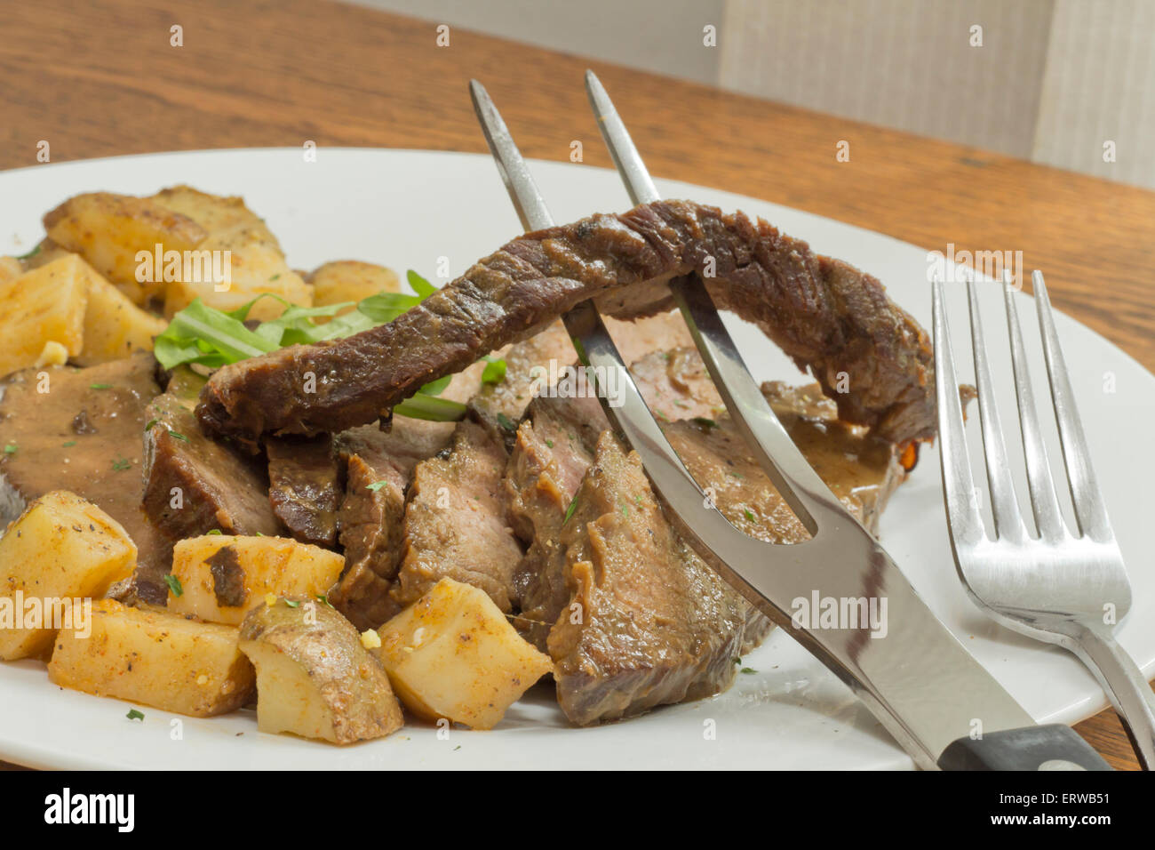 In Scheiben geschnitten saftiges Rock Steak mit Kartoffeln und Rucola garnieren Stockfoto