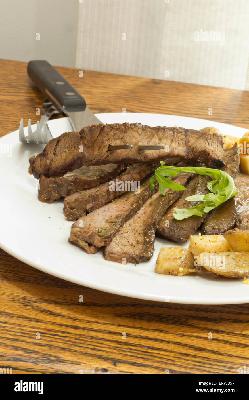 In Scheiben geschnitten saftiges Rock Steak mit Kartoffeln und Rucola garnieren Stockfoto