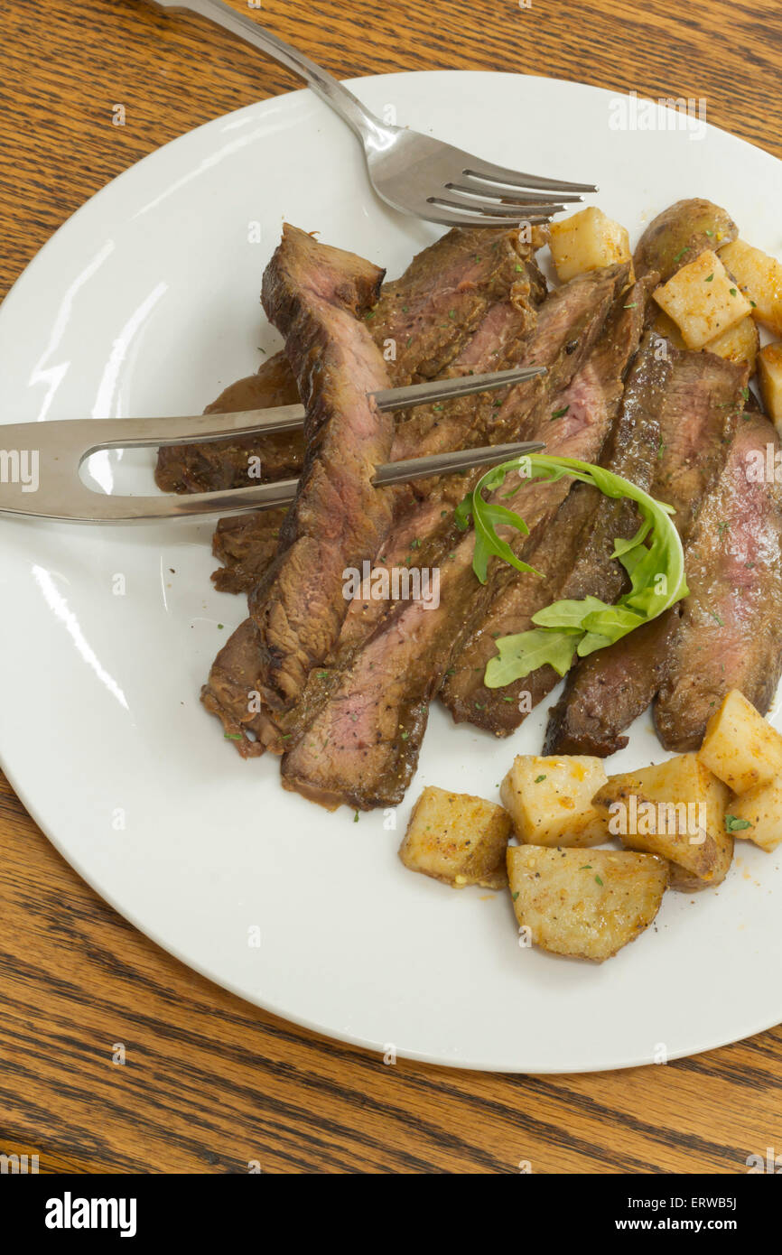In Scheiben geschnitten saftiges Rock Steak mit Kartoffeln und Rucola garnieren Stockfoto