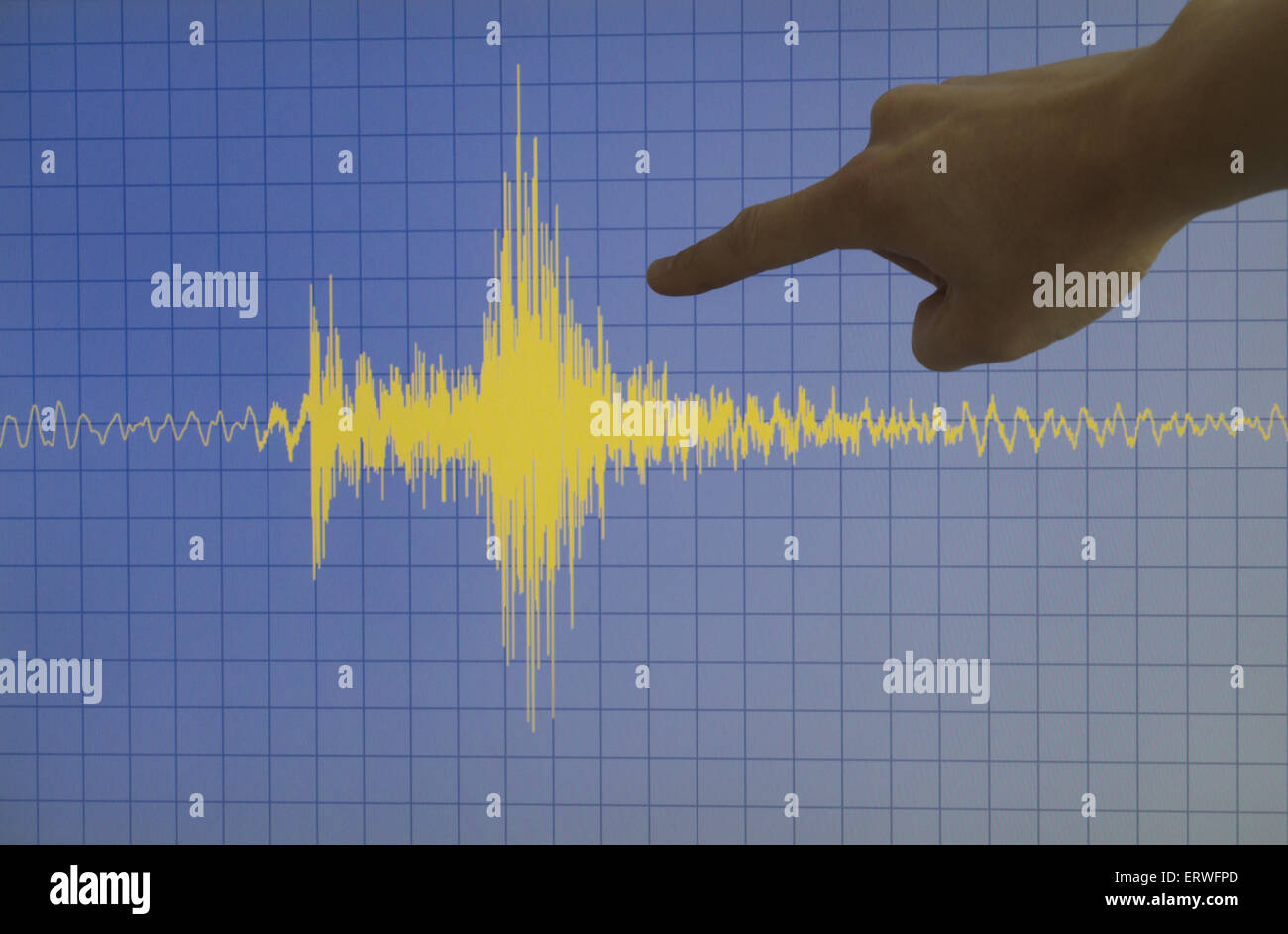 Hand zeigt eine gelbe Erdbeben mit blauem Hintergrund und ein Raster Stockfoto