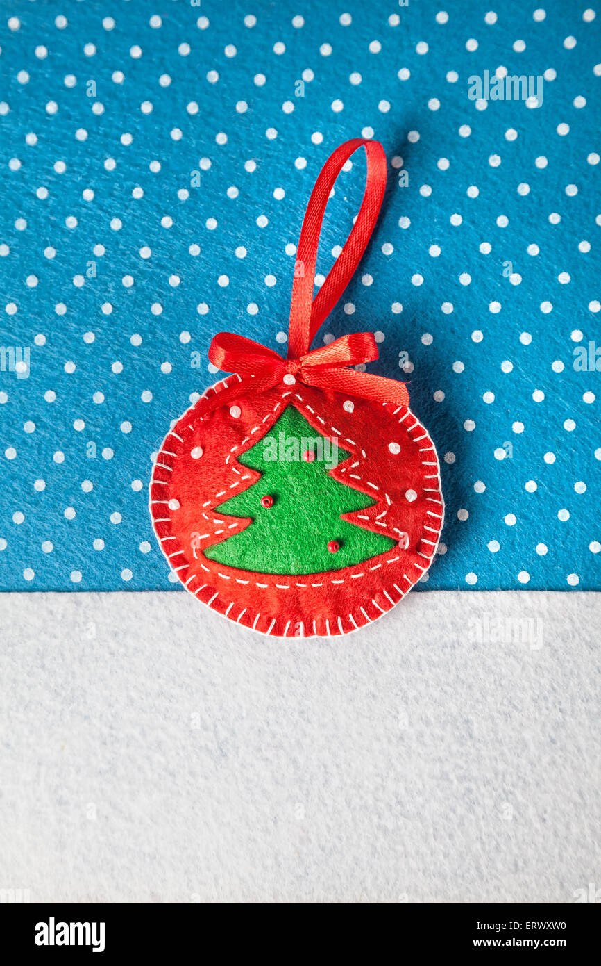 Handgemachte Spielzeug mit Weihnachtsbaum aus Filz auf blauem Hintergrund mit Schneeflocken Stockfoto