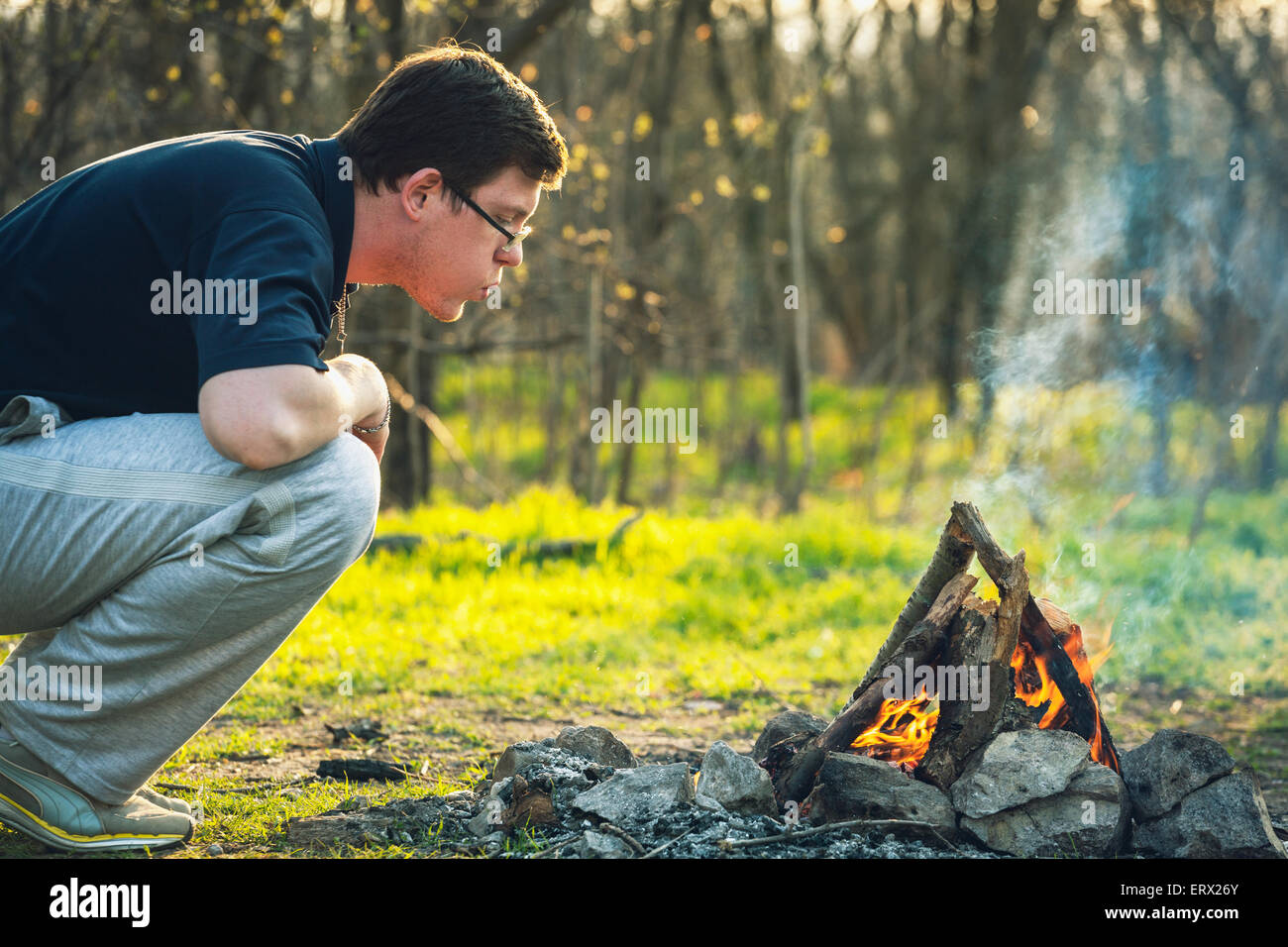 Mann und Lagerfeuer im Frühlingswald. Kohlen. Sonnenuntergang in der Ukraine Stockfoto