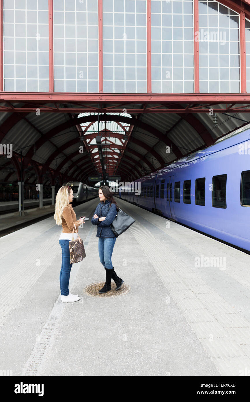 Freundinnen, die gemeinsam am Bahnhof stehen Stockfoto