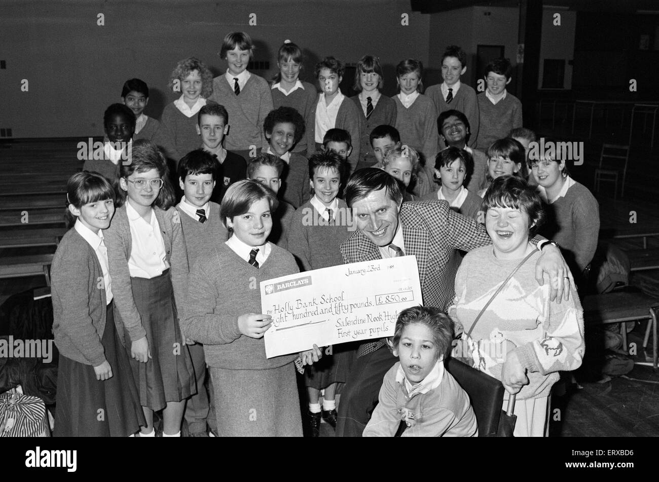Schüler von Salendine Nook High School präsentieren einen Scheck im Wert von 850 Poounds John Proctor, kommissarischer Leiter der Holly Bank Schule, für ihre neuen Räume in Mirfield, 26. Januar 1989. Stockfoto