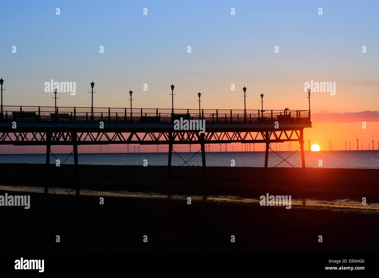 Skegness Pier, bei Sonnenaufgang, im Juni. Windpark in der Ferne zu sehen. In Skegness, Lincolsnhire, England Stockfoto
