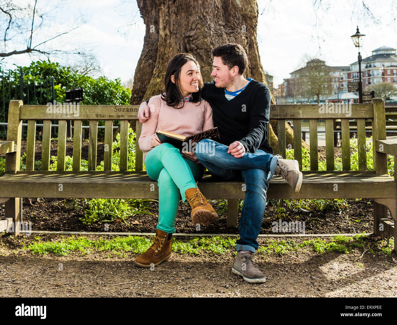 Paar in Liebe umarmt und Dating sitzen auf einer Bank in einem Park sahen einander Stockfoto
