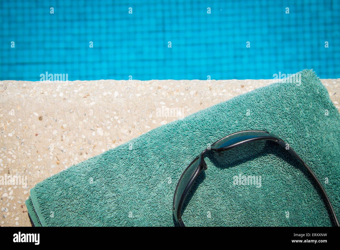 Sonnenbrillen und Handtuch am Rand des Swimming pool Stockfoto