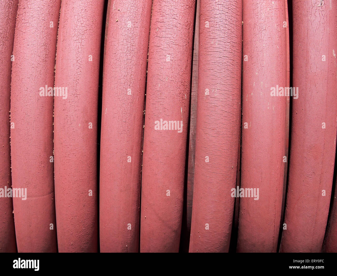 Nahaufnahme einer abgenutzten Spule Gartenschlauch zeigt Risse an der Oberfläche des roten Gummis. Stockfoto