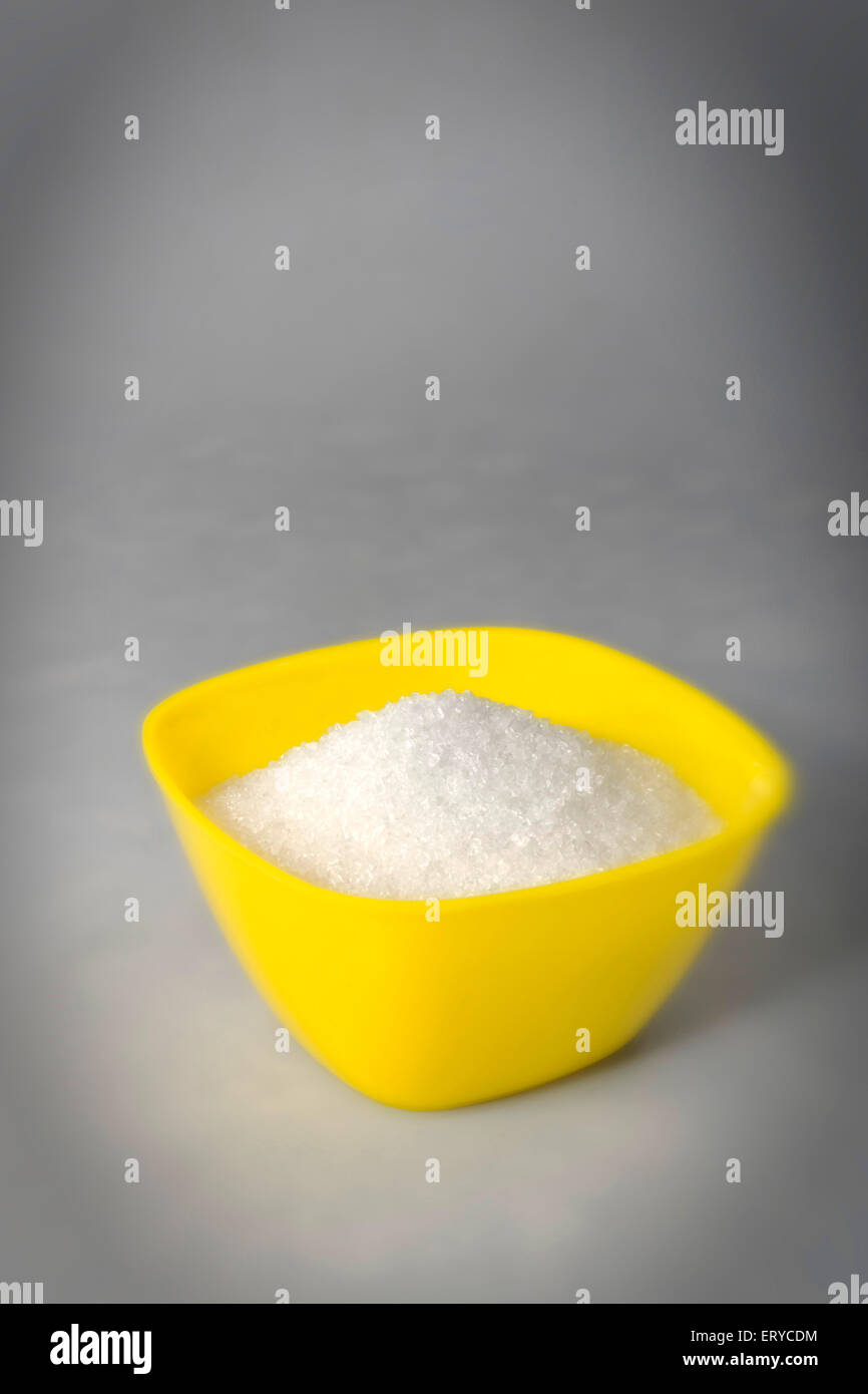 Zucker in gelbe Plastikbox auf grauem Hintergrund Stockfoto