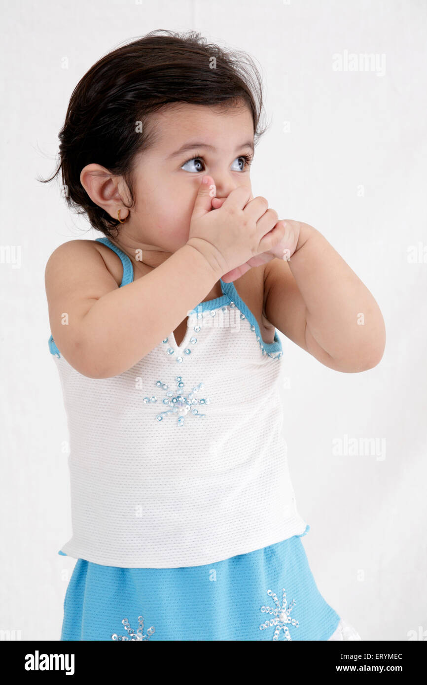 Fünfzehn Monate altes Babymädchen posiert beide Hände auf den Mund schauen seitwärts Herr #743S Stockfoto