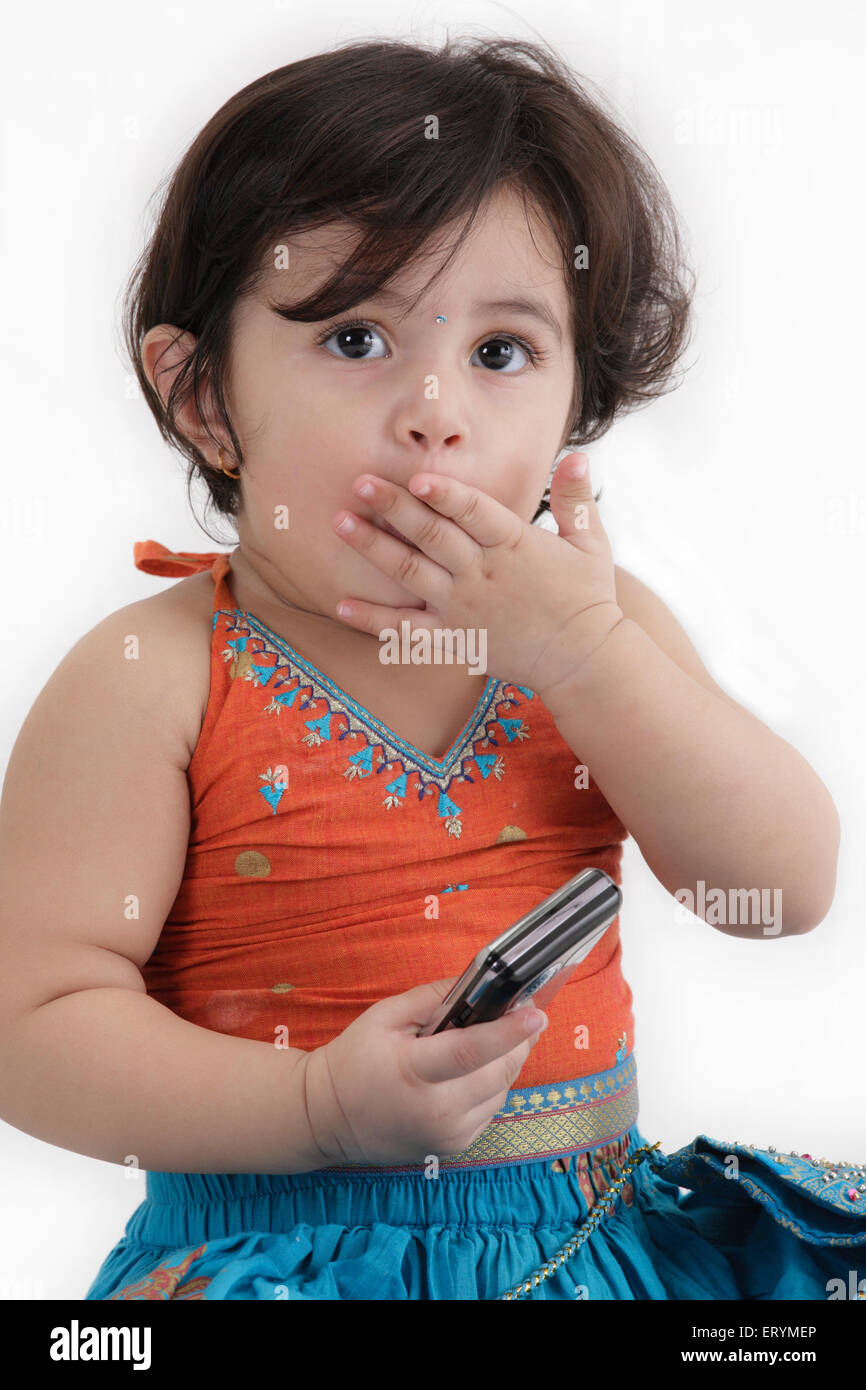 Fünfzehn Monate altes Baby Mädchen in pâvadèï Choli posiert einerseits Mund mobile in der anderen Hand Herr #743S Stockfoto