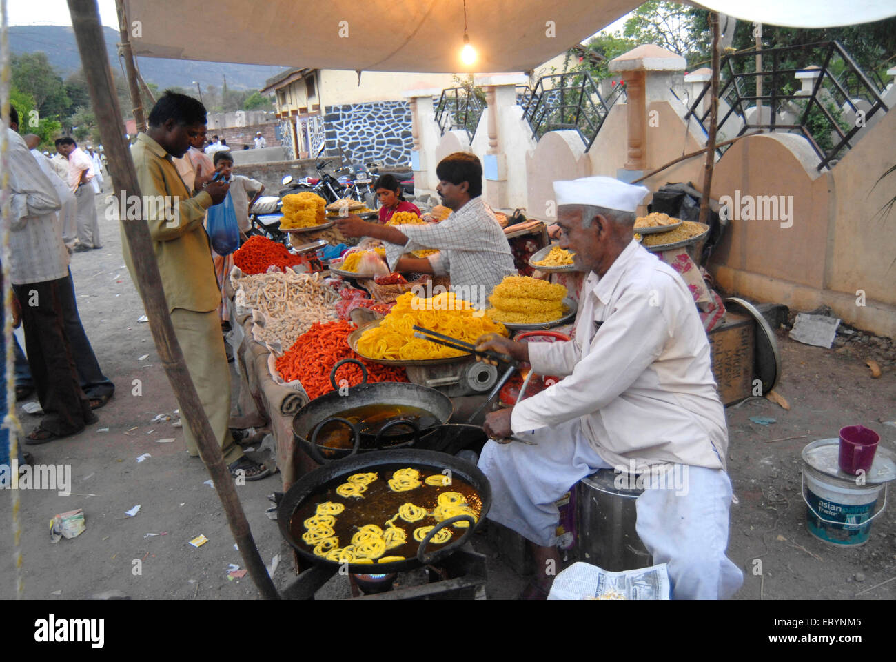 Ein Dorfbewohner bereitet die Jalebis; eine Süßspeise und andere Süßspeisen zum Verkauf während einer lokalen Messe im Dimba Village; District Pune Stockfoto