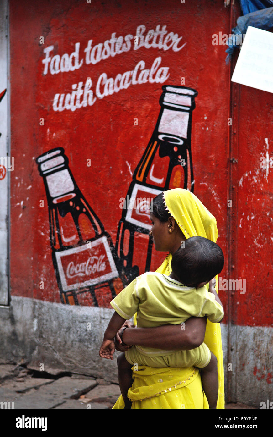 Coca Cola Werbung an der Wand gemalt , Frauen tragen Kind , Bombay , Mumbai ; Maharashtra ; Indien , Asien Stockfoto