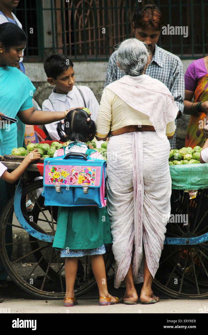 Schulmädchen mit Großmutter kaufen Obst in Bombay Mumbai; Maharashtra; Indien Stockfoto