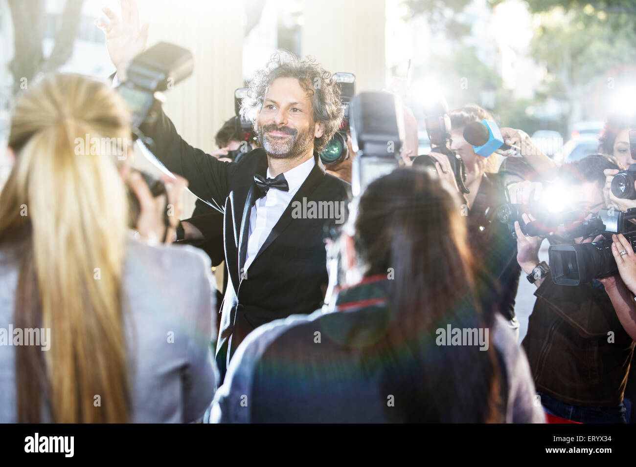 Berühmtheit winkt Paparazzi-Fotografen bei Veranstaltung Stockfoto