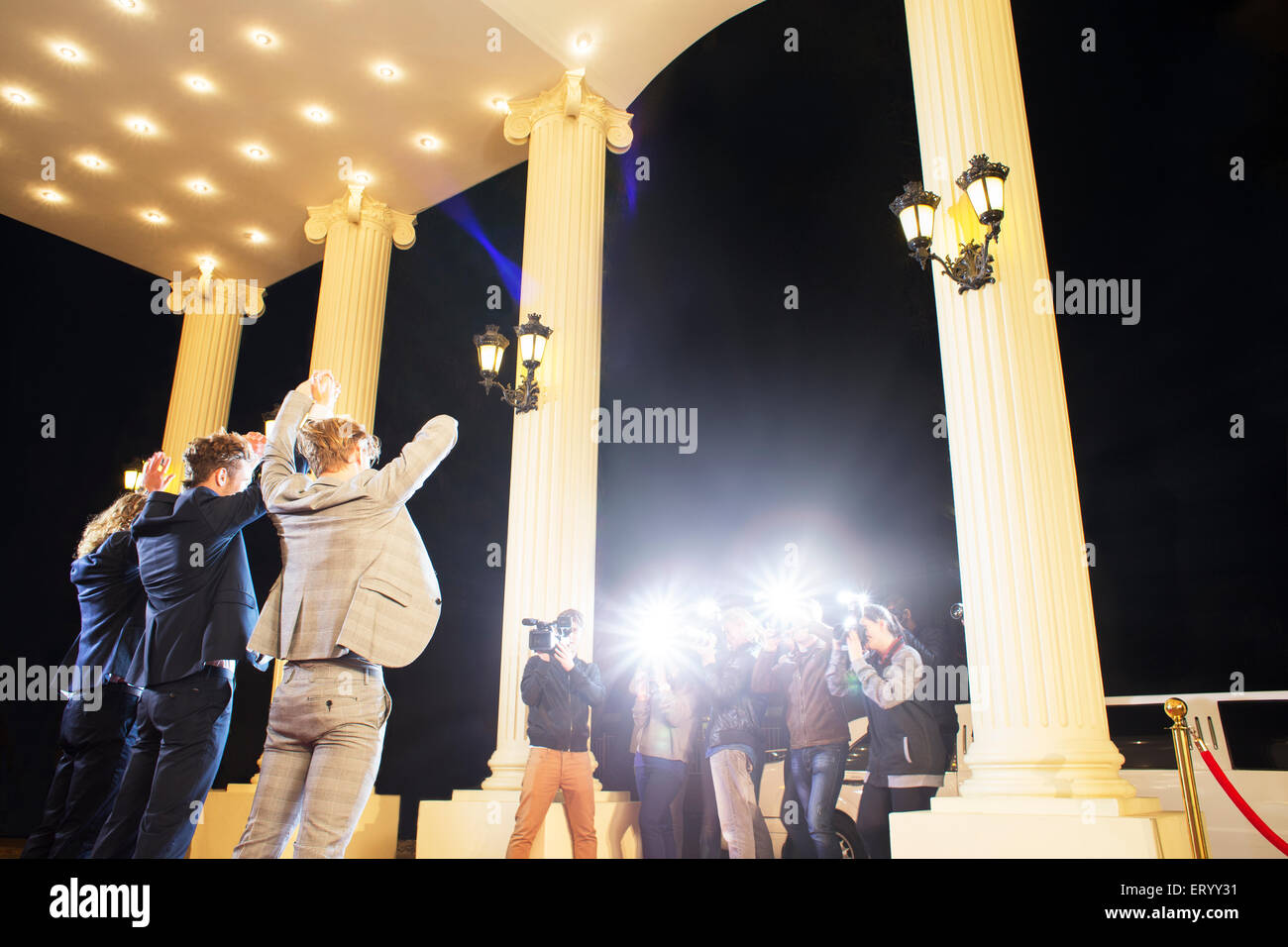 Prominente posiert mit für Paparazzi-Fotografen bei erhobenen Armen Stockfoto