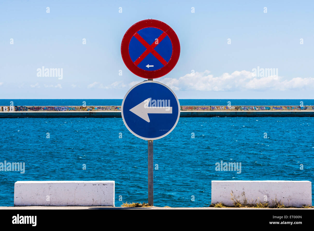 Kein Parkplatz-Zeichen und ein weiteres Zeichen der obligatorischen Richtung mit dem Meer und Himmel Hintergrund Stockfoto