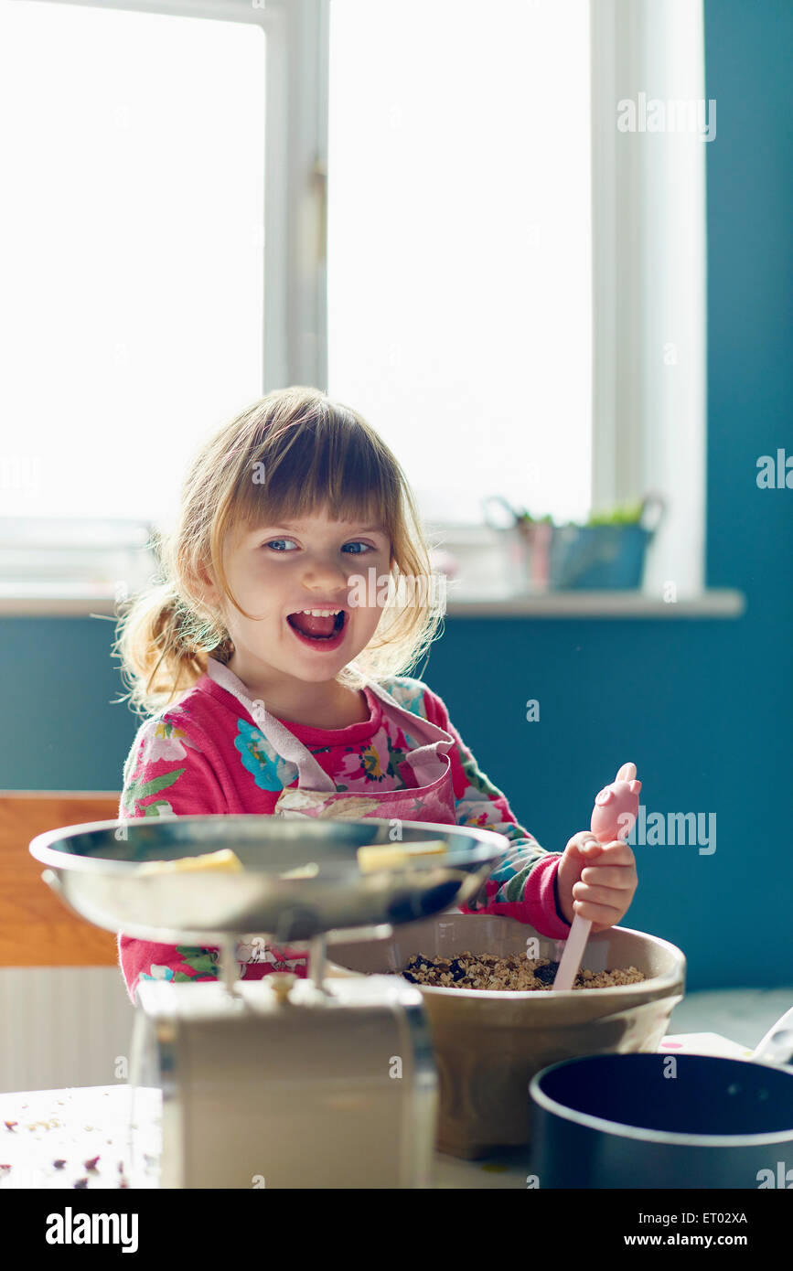 Lächelndes Mädchen Backen mit Rührschüssel in Küche Stockfoto
