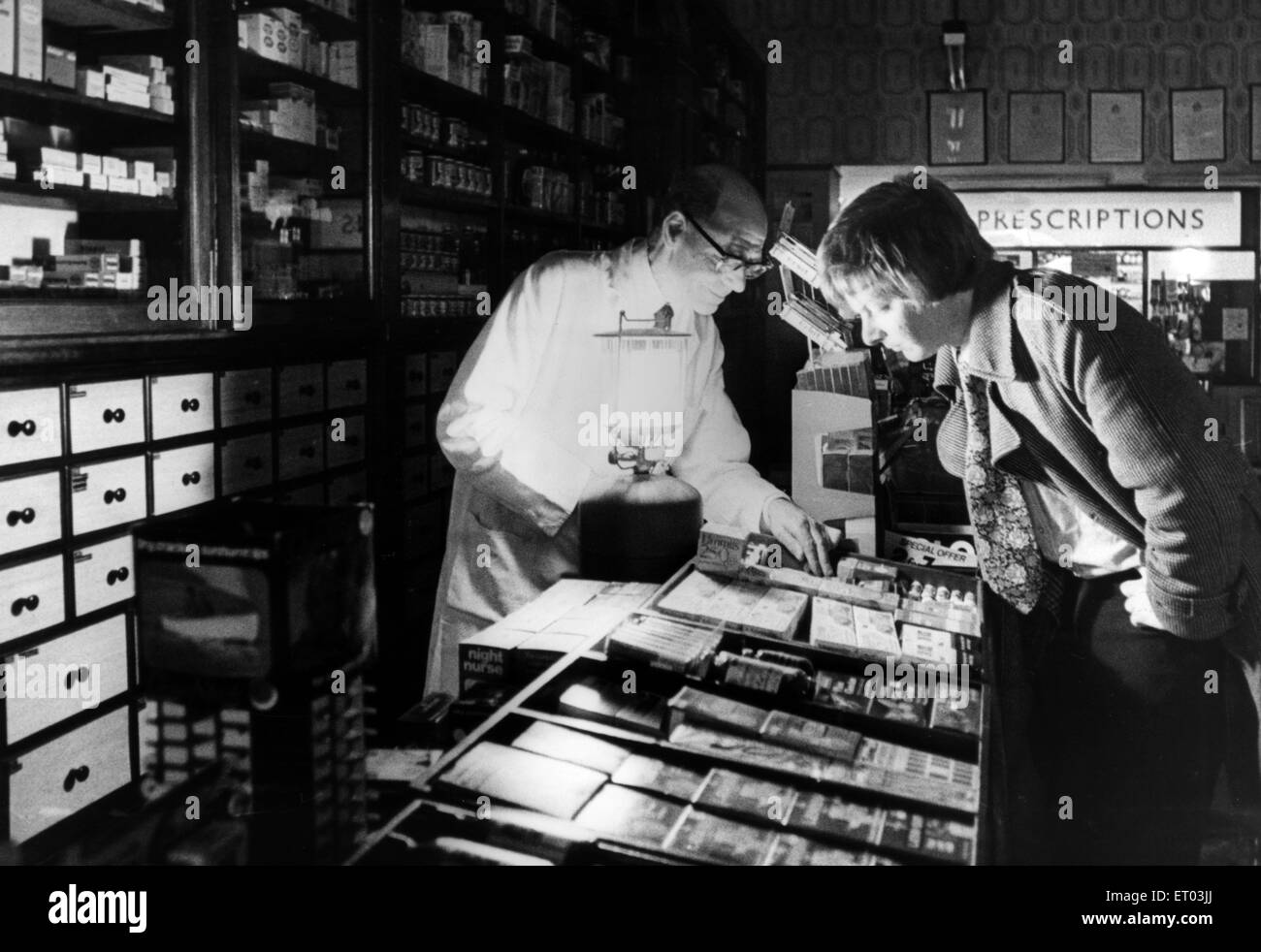 Shopping während Powercuts, ist James Taylor in der Lage, seine Apotheke offen zu halten, mit Notbeleuchtung bei Stromausfall, 2. November 1977. Stockfoto