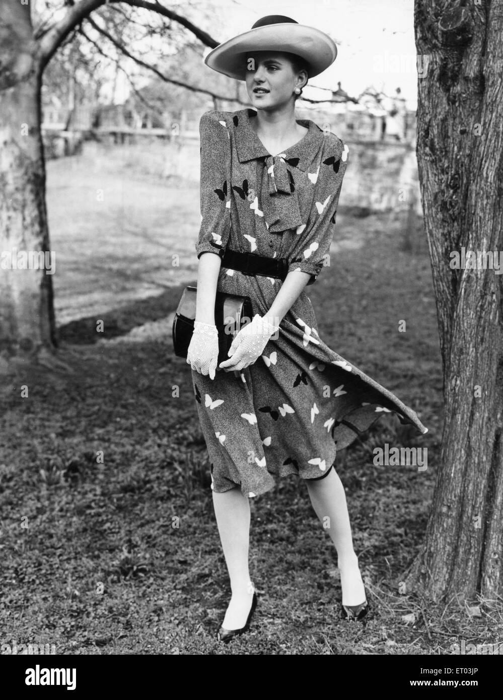 die 1980er Jahre Damenmode: unser Model trägt ein Schmetterling Motiv mit Gürtel Kleid und Hut mit Spitzenhandschuhe und eine schwarze Lederhandtasche. 8. April 1985 Stockfoto