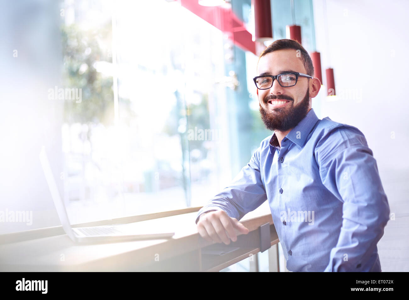 Porträt von lächelnden Geschäftsmann mit Bart am Laptop im café Stockfoto