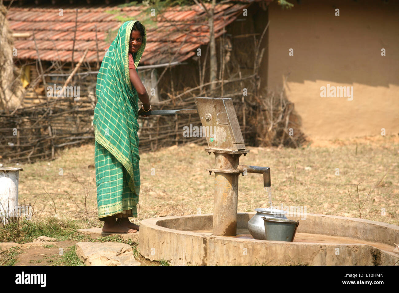 Indische Landfrau, die Wasser aus der Dorfhandpumpe füllt, Ranchi, Jharkhand, Indien Stockfoto