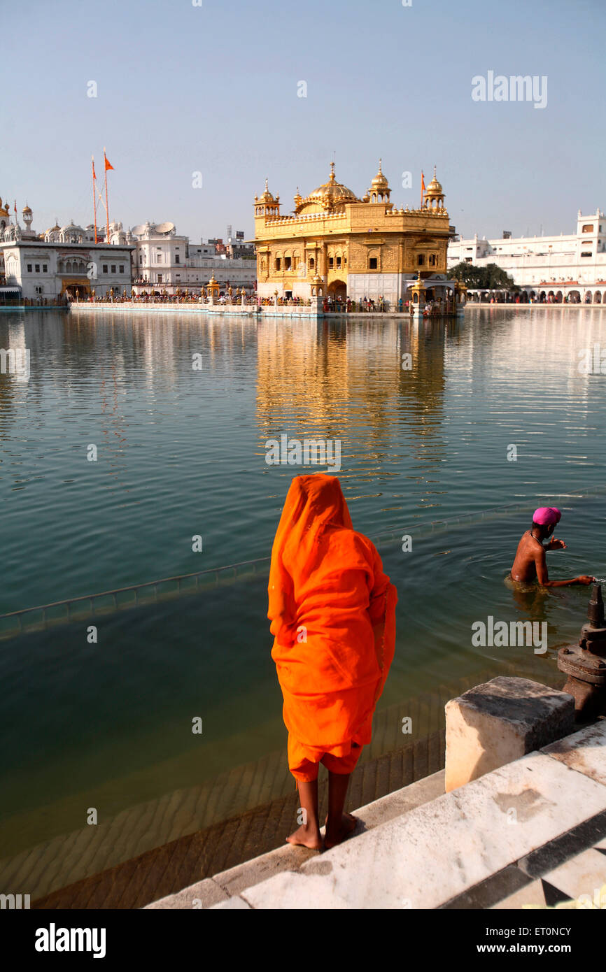 Junge unter Dip und Frau stehende Rand des Sees am Harmandir Sahib oder Darbar Sahib oder goldenen Tempel in Amritsar; Punjab; Indien Stockfoto