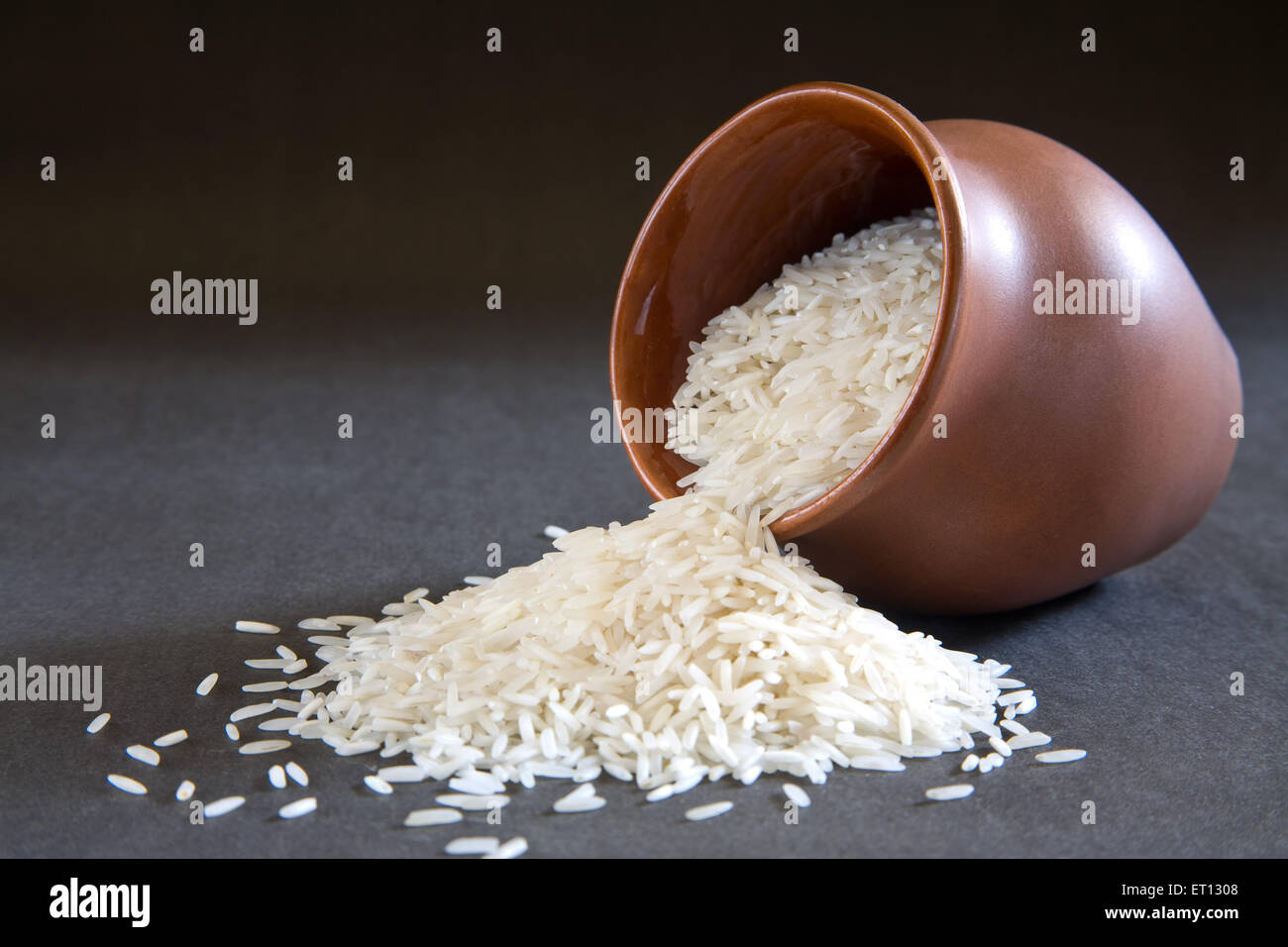 Basmati-Reis im Erdtopf auf schwarzem Hintergrund verteilt Stockfoto