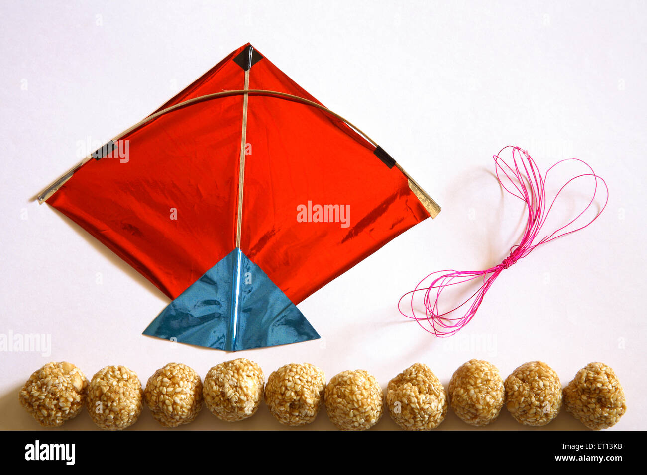 Kite-Thread und süße Tilgur oder til Gul Sesam Laddoos für Makara Sankranti Festival auf weißem Hintergrund Stockfoto
