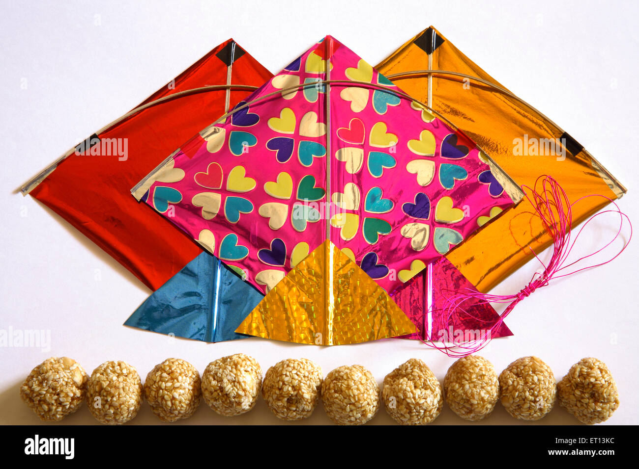 Bunte Drachen Thread und süßen Tilgur oder til Gul Sesam Laddoos für Makara Sankranti Festival auf weißem Hintergrund Stockfoto