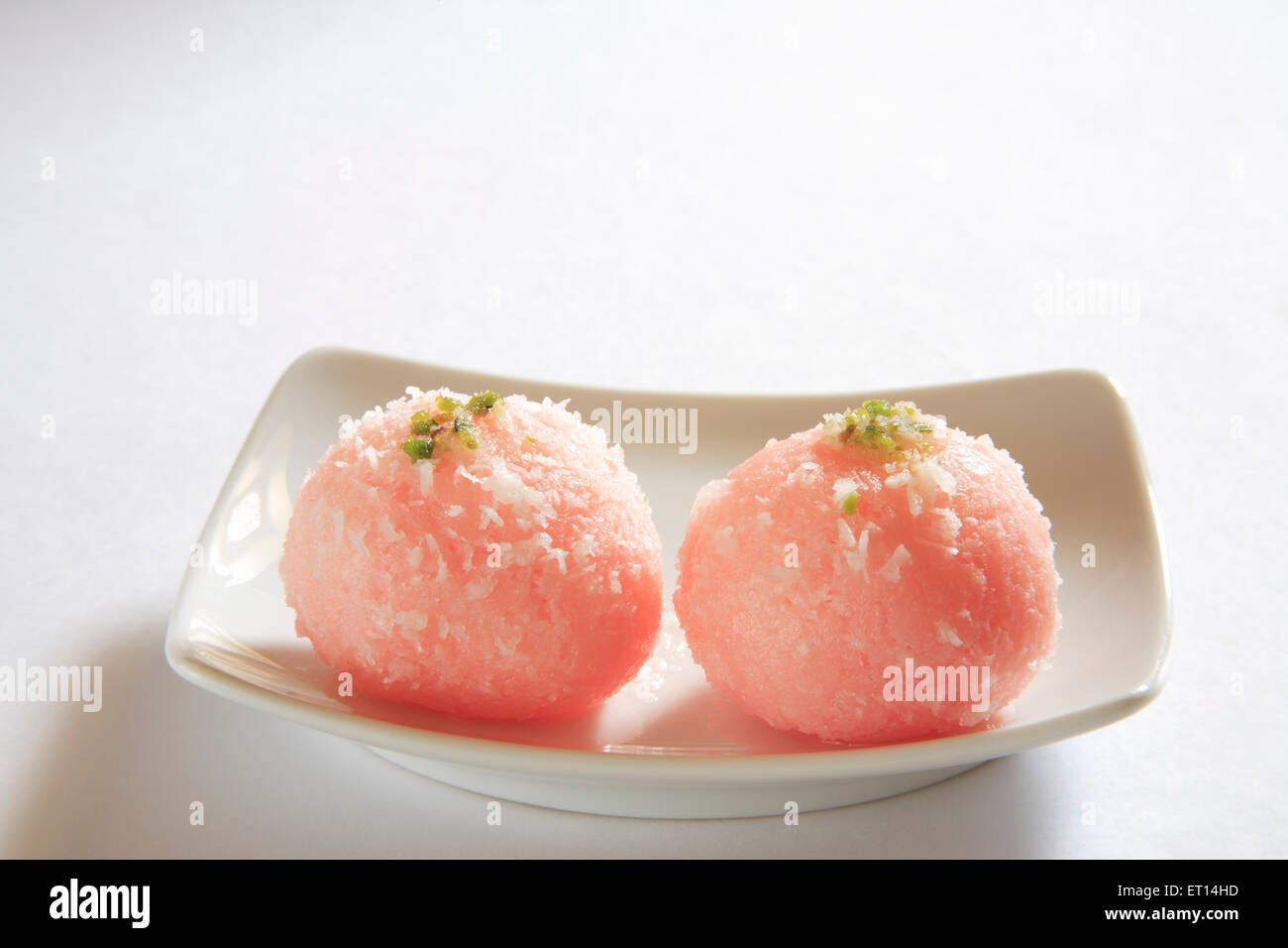 Zwei Stücke von bengali Kozhikode Raskadam garniert mit Kokos und Pistazien in Rechteck Platte auf weißem Hintergrund Stockfoto