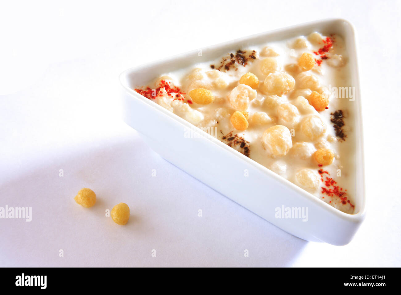 Indisches Dessert, boondi raita gewürzt mit Chilipulver in Dreieck Platte auf weißem Hintergrund Stockfoto