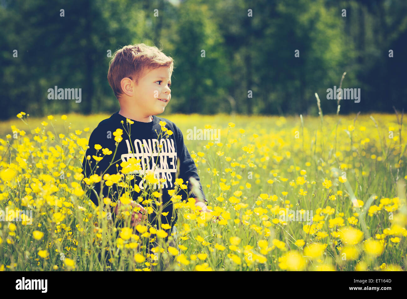 kleine süße junge Kind in einem wunderschönen gelben Blüten, Lächeln und lachen Stockfoto