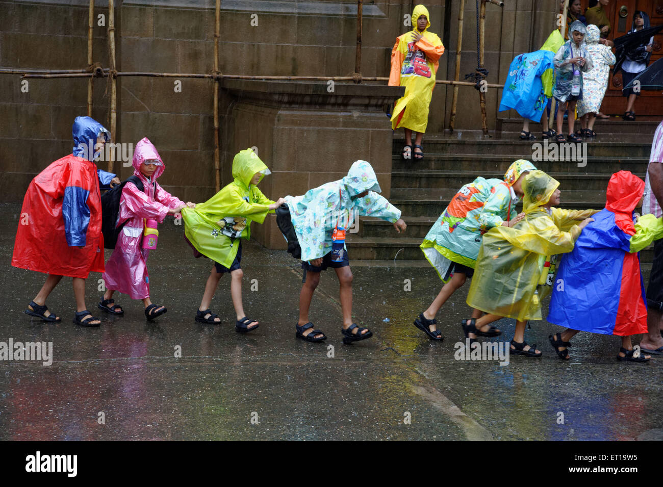 Schulkinder tragen bunte Regenmäntel in Linie Mumbai Maharashtra Indien Kinder im Regen Stockfoto