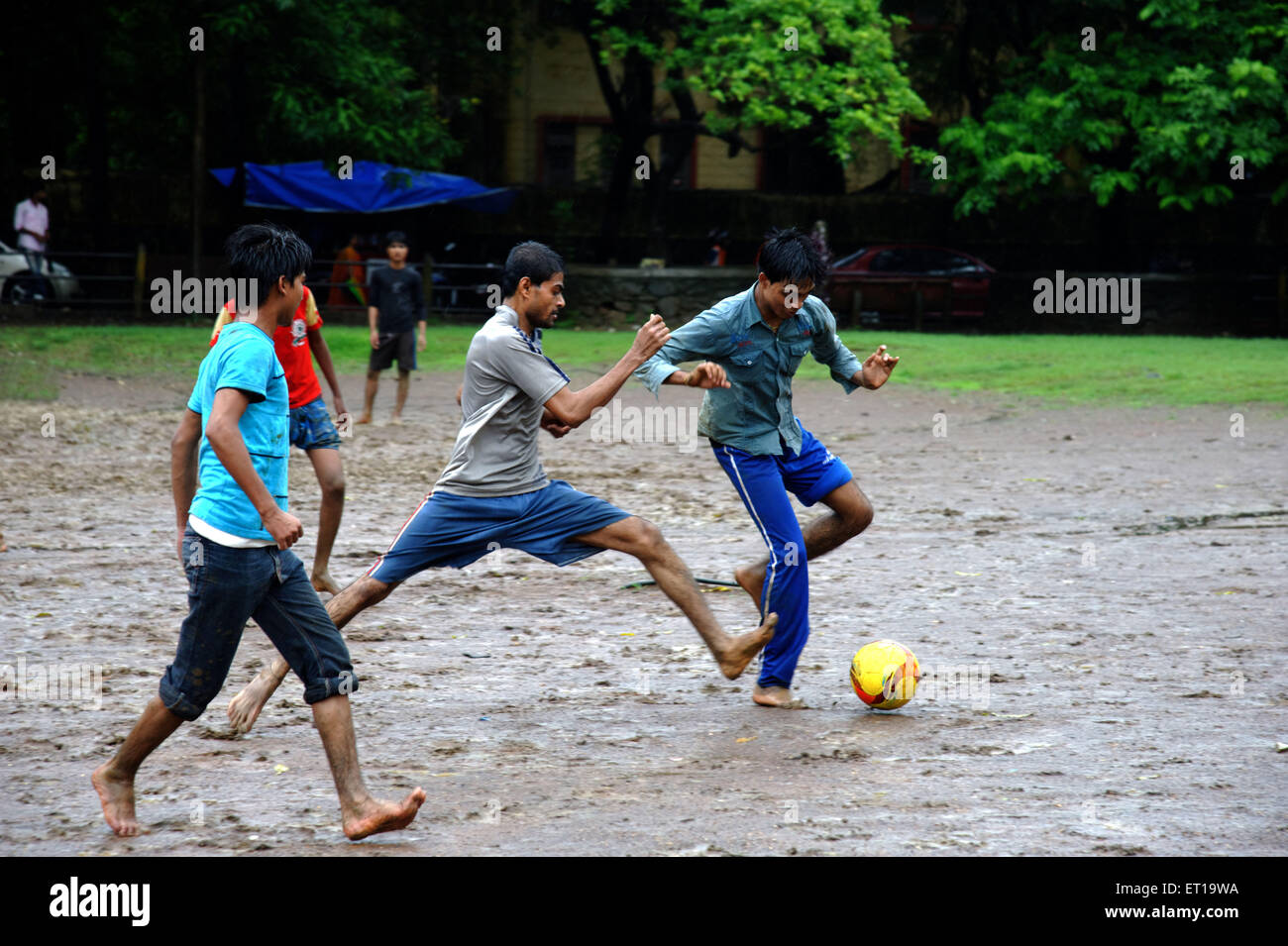 Jungs spielen Fußball im Regen Stockfoto