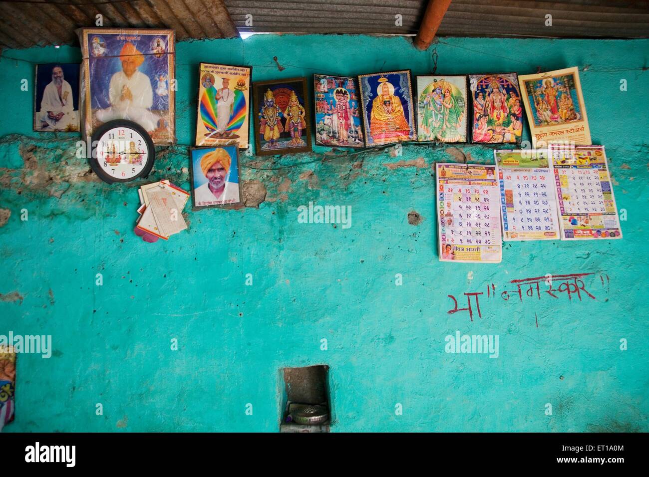 Fotos von Göttern und Kalendern an der Wand im Haus; Nandur; Marathwada; Maharashtra; Indien Stockfoto