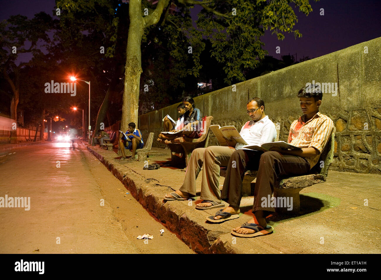 Studenten, die unter Straßenbeleuchtung auf Bürgersteig, Abhiyas Galli, Bombay, Mumbai, Maharashtra, Indien, Asien, Asien, Indien Stockfoto