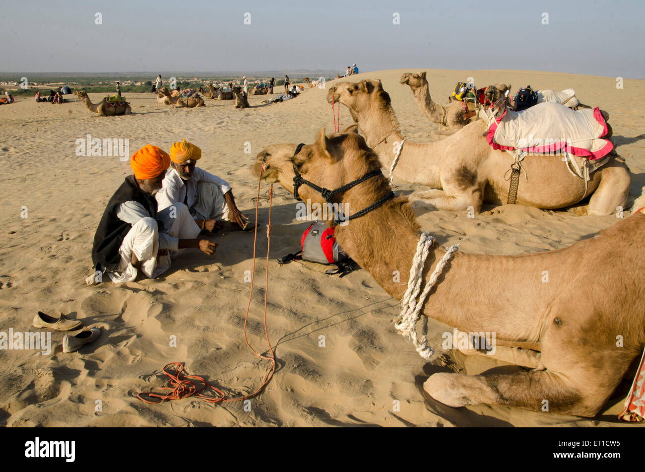 Männer und Kamel sitzen auf Sand Düne wartet auf Touristen Safari in Khuri in Jaisalmer, Rajasthan Indien Asien Stockfoto