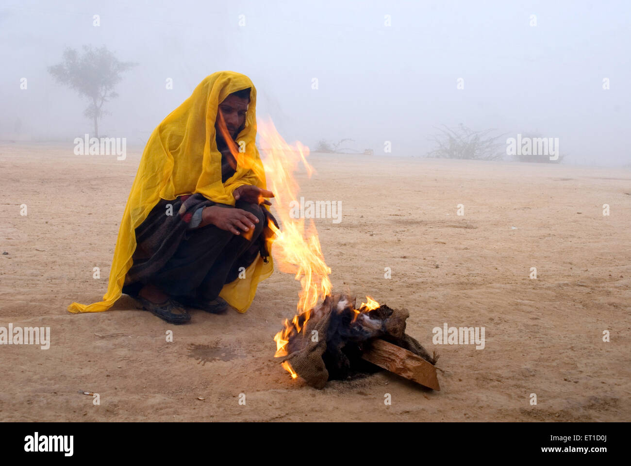 Mann mit gelben Tuch Feuer Aufwärmen; Jodhpur; Rajasthan; Indien NOMR Stockfoto