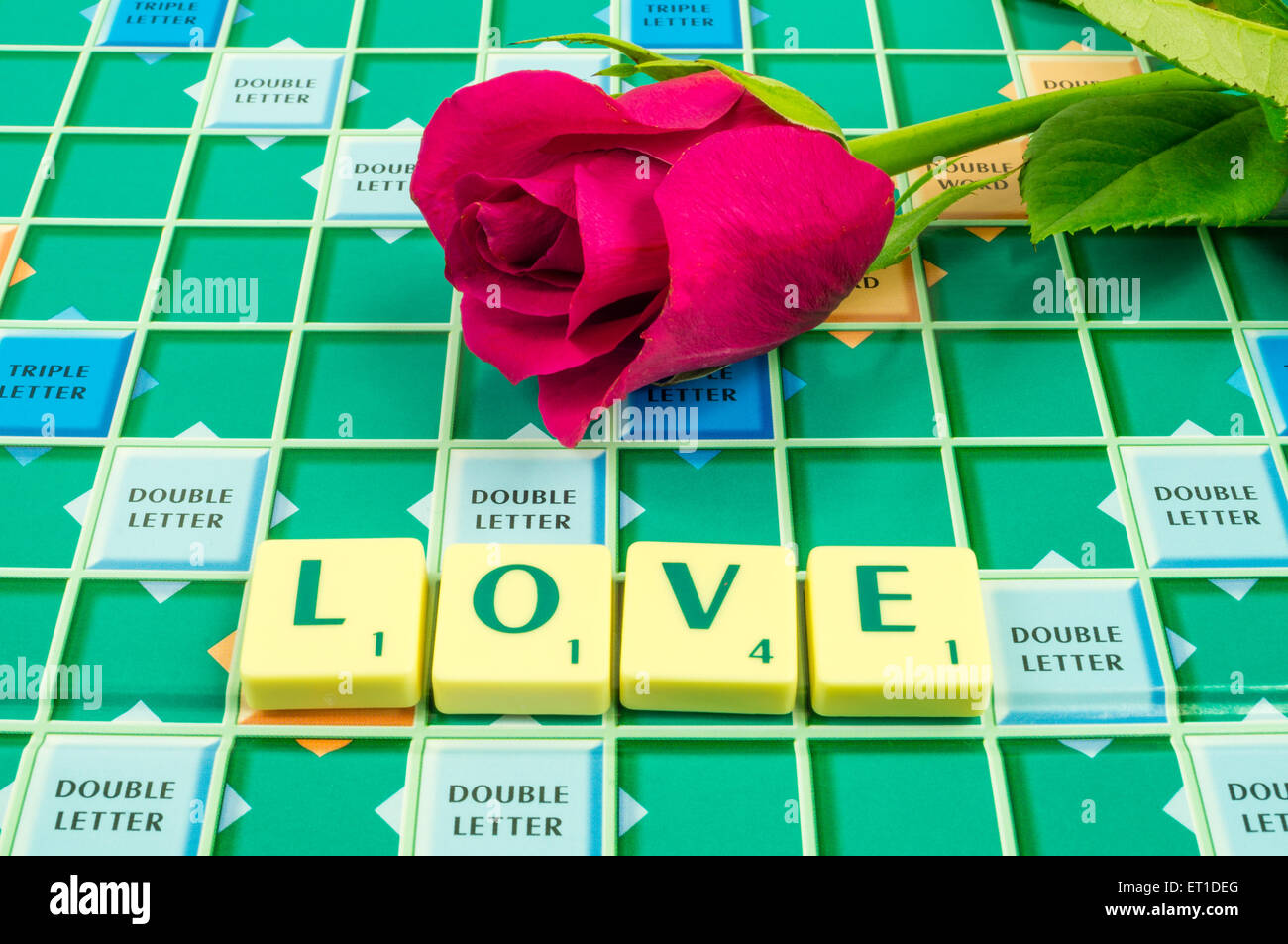 Das Wort Liebe auf einem Scrabble-Brett mit einer roten rose Stockfoto