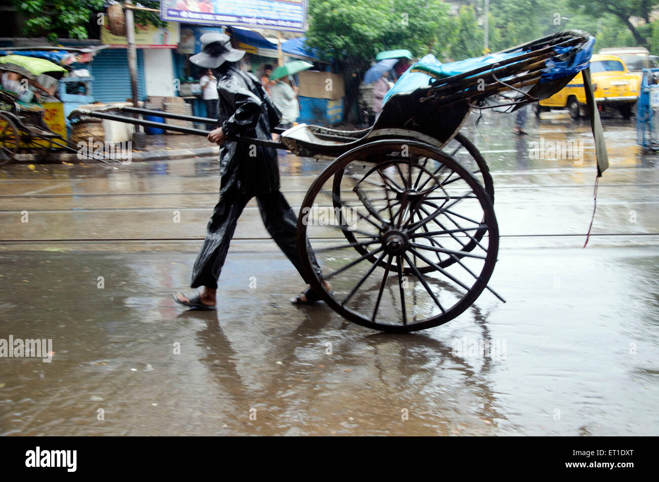 Mann im Regenmantel ziehen Hand Rikscha auf Straße in Kalkutta in West Bengal Indien Asien Stockfoto