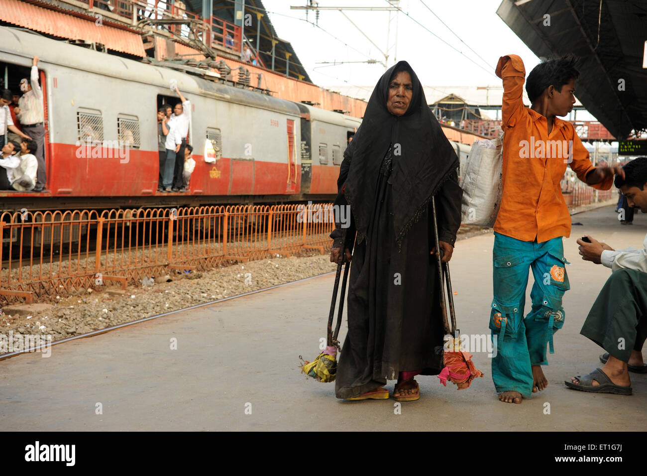 Behinderte, behinderte muslimische Frau mit Krücken auf Bahnsteig, Bombay, Mumbai, Maharashtra, Indien Stockfoto