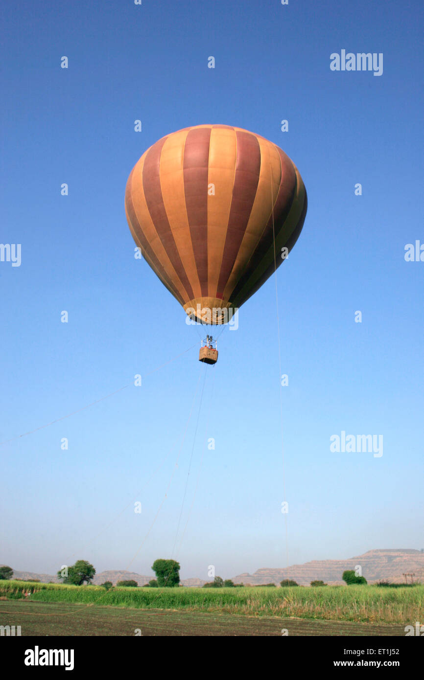 Braun bunt gestreiften Heißluftballon fliegen über Zuckerrohr Betriebe; Wai; Maharashtra; Indien Stockfoto