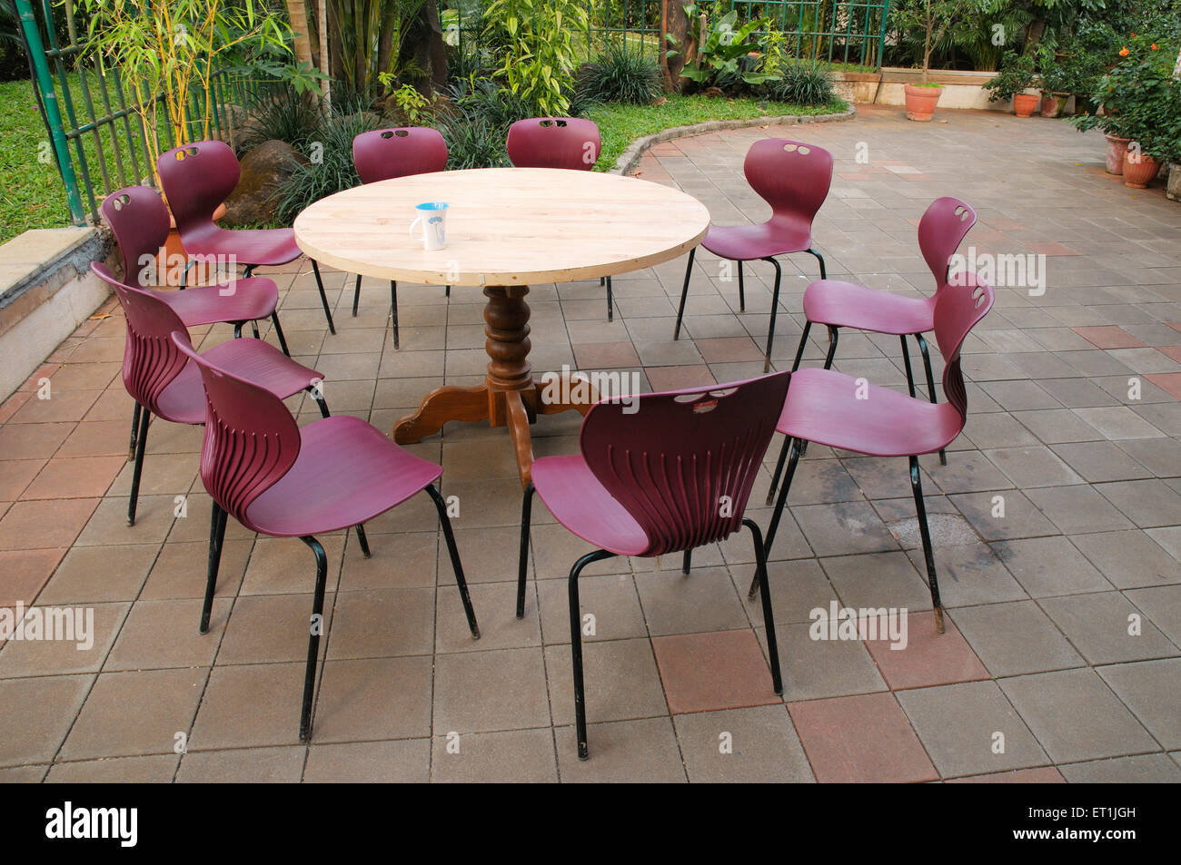 Runder Holztisch mit zehn Plastikstühlen im Garten Stockfoto