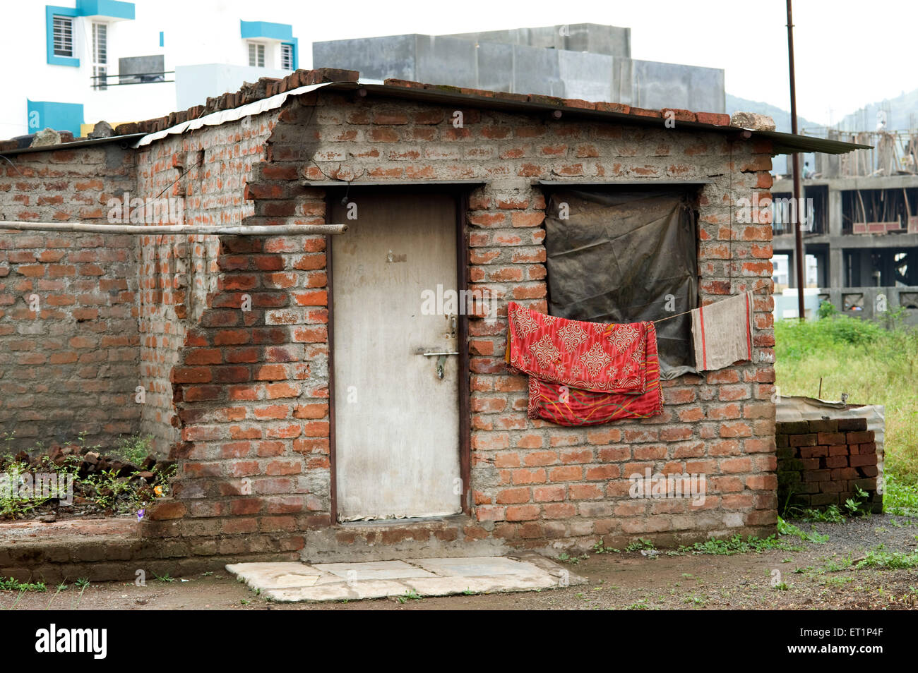 Freiliegende Ziegelwand Haus geschlossene Tür Kunststoff-Fenster Wäsche trocknen Indien Stockfoto