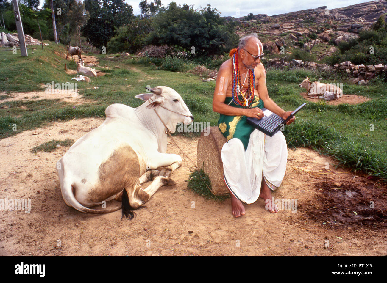 Sanskrit Gelehrter mit Computer-Laptop und Kuh, Melkote, Melukote, Thirunarayanapuram, Pandavapura taluk, Mandya Bezirk, Karnataka, Indien, Asien Stockfoto
